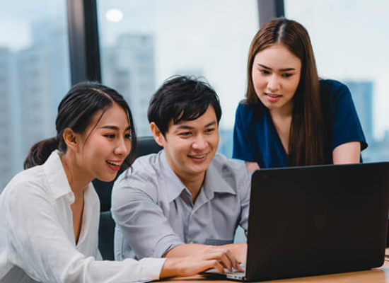 Three colleagues looking at laptop screen with statistics